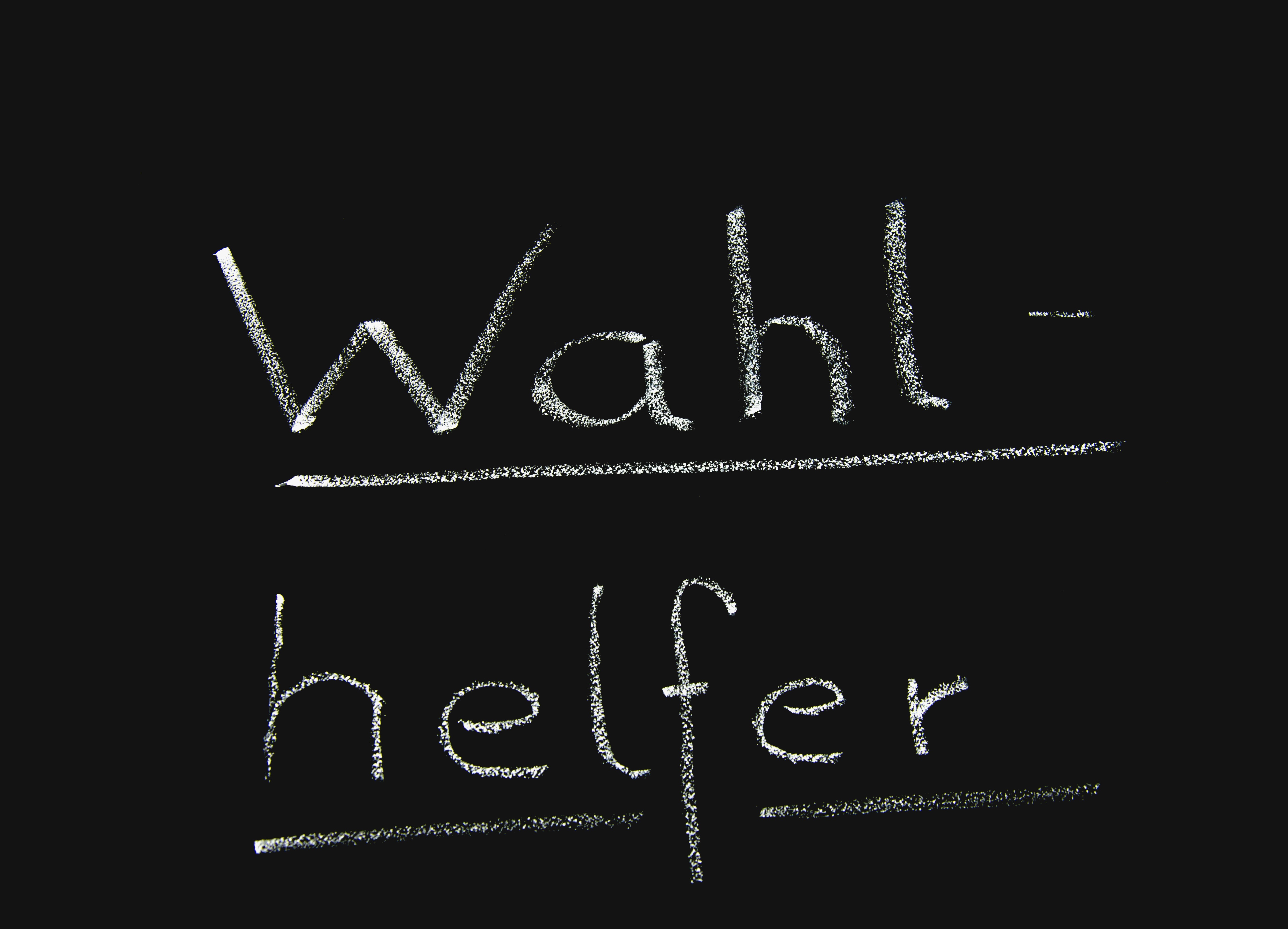 Schwarze Tafel mit Kreide Aufschrift Wahlhelfer