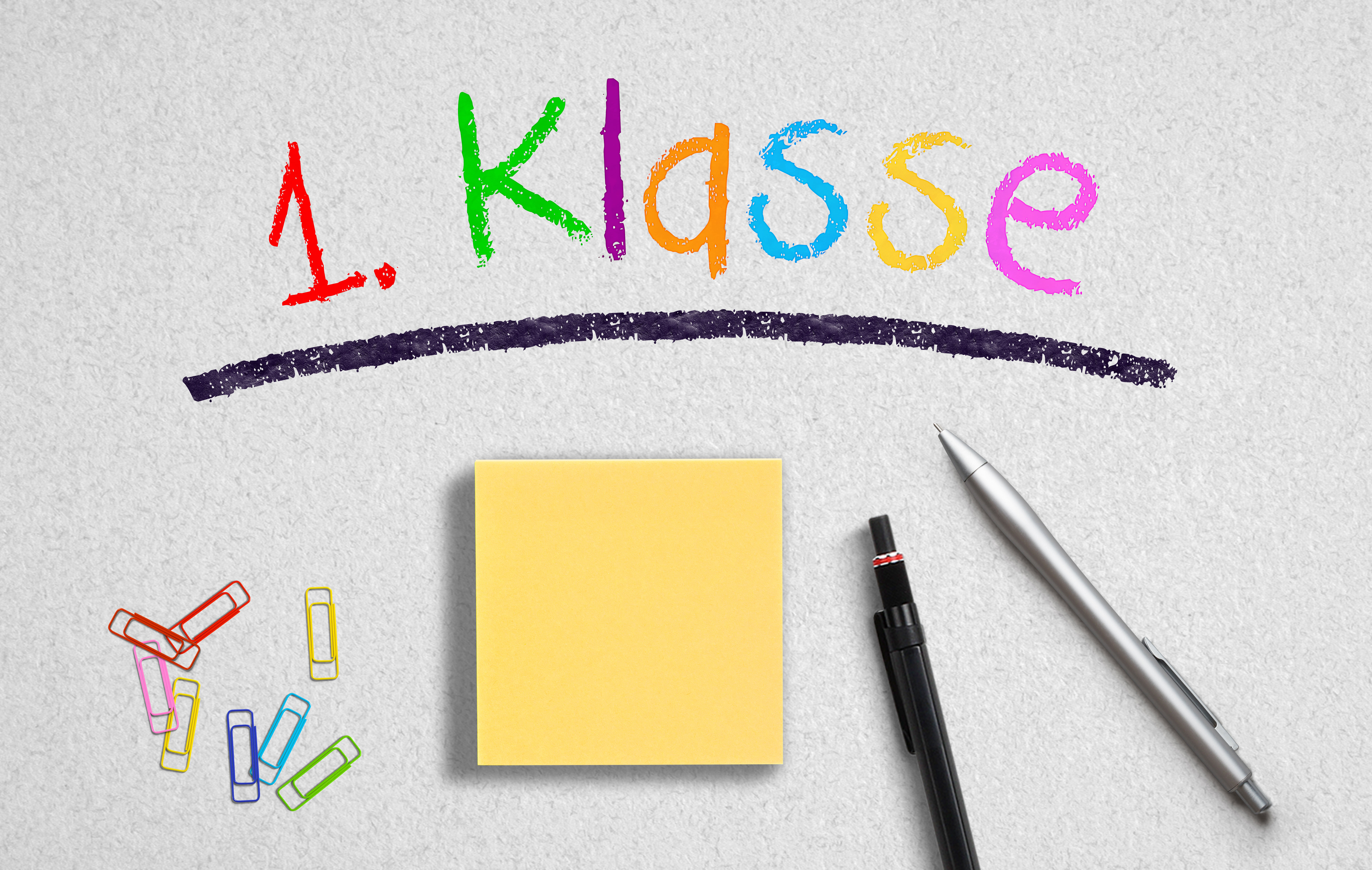 Büroutensilien auf Papieruntergrund mit Aufschrift "1. Klasse"