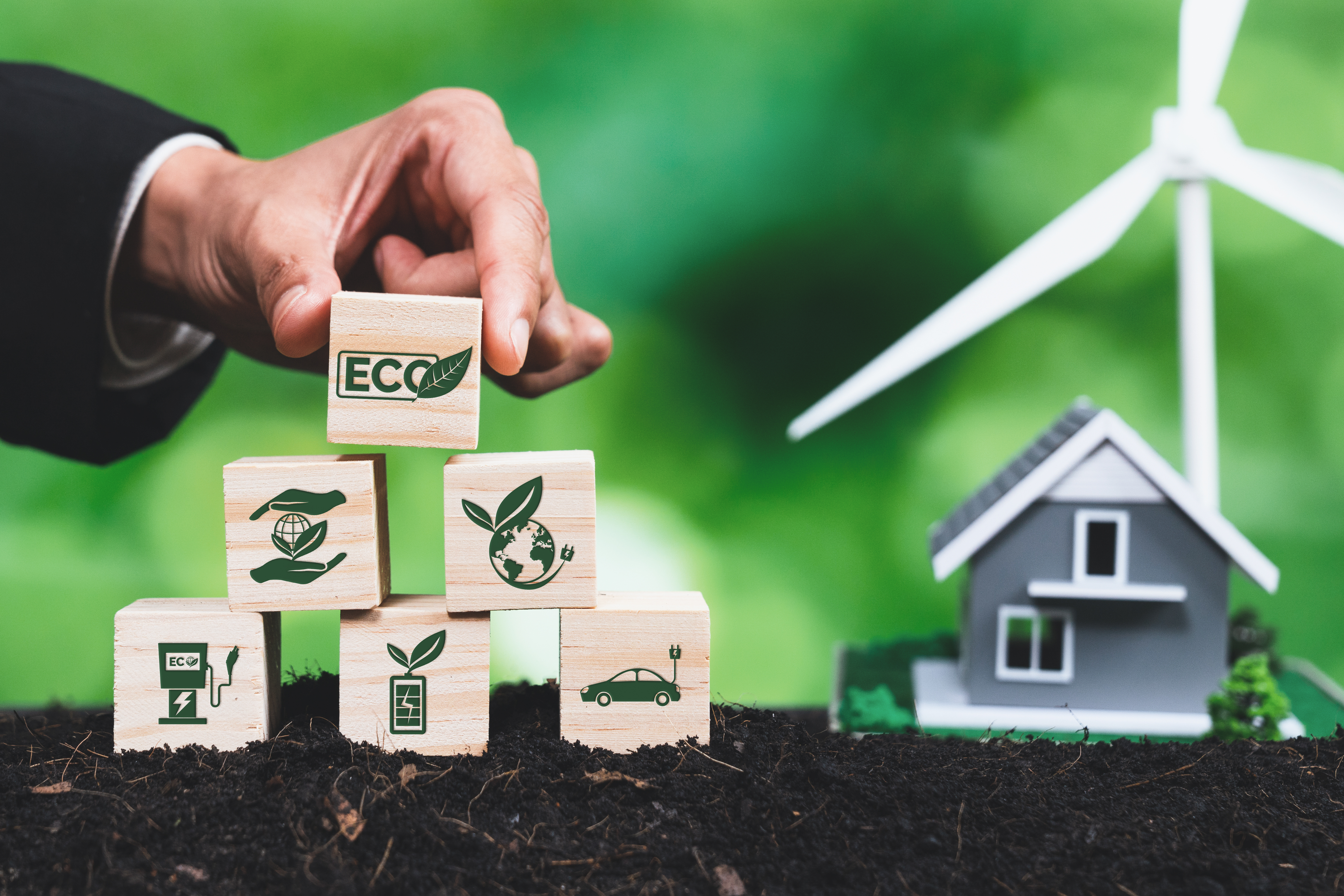 Businessman put ECO symbol on pyramid top with house and wind turbine. Alter