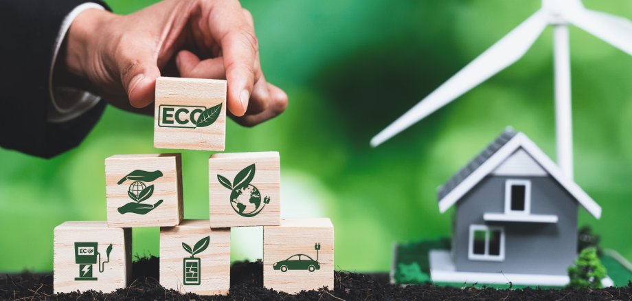 Businessman put ECO symbol on pyramid top with house and wind turbine. Alter