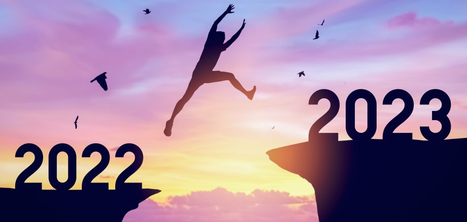 Silhouette man jumping between cliff with number 2022 to 2023 an