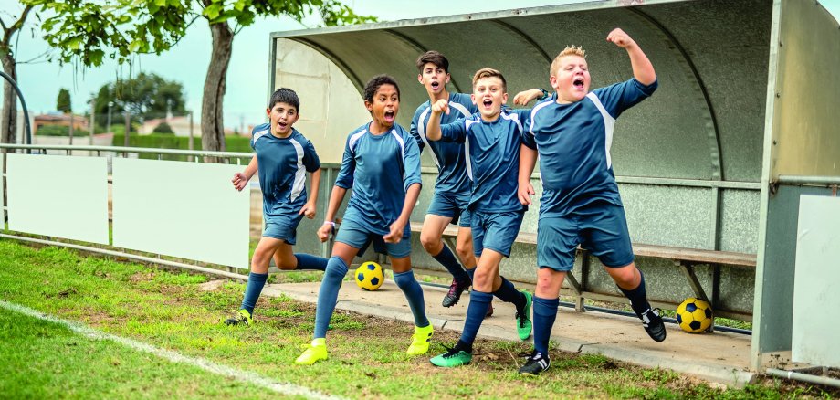 Energetic Boy Footballers Cheering From Sideline Bench